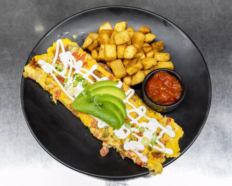 Omelet topped with avocado, sour cream, and green onions, served with home fries and salsa.