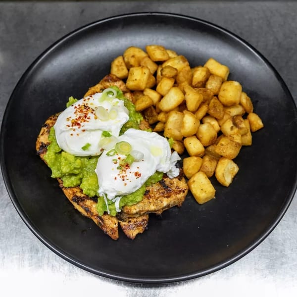 Grilled chicken topped with guacamole, poached eggs, and a side of crispy home fries.