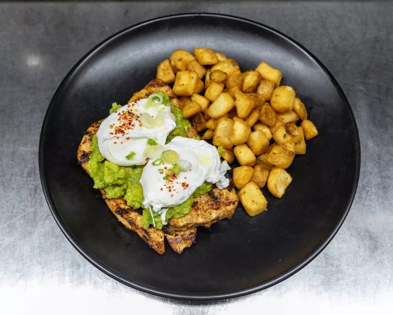 Grilled chicken topped with guacamole, poached eggs, and a side of crispy home fries.